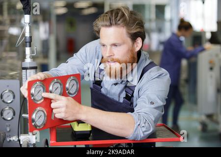 man pointing at machine valves Stock Photo