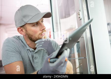 locksmith holding tablet and screwdriver Stock Photo