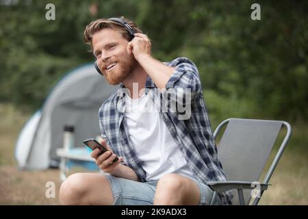 man in camping with tent using phone listen to music Stock Photo