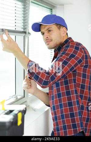 handyman installing slatted window blinds Stock Photo