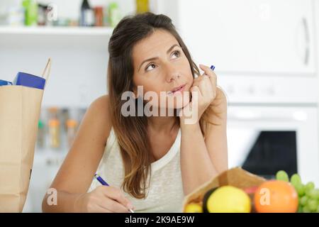 woman writing a list in her kitchen Stock Photo