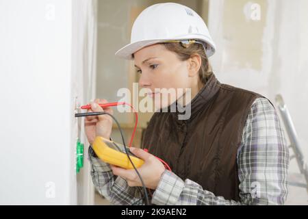 electrician checking socket voltage using multimeter Stock Photo