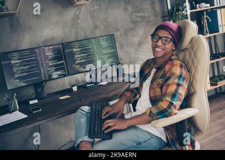 Photo of smiling happy guy dressed eyewear hat chatting modern device indoors workstation workshop home Stock Photo