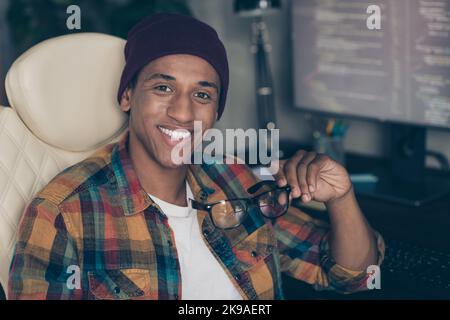 Photo of smiling cheerful freelancer wear hat glasses creating modern technologies indoors workplace workstation loft Stock Photo