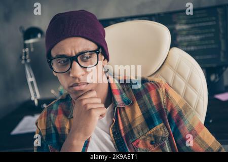 Photo of ponder pensive freelancer wear hat glasses thinking code problem solving indoors workplace workstation loft Stock Photo