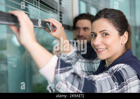 happy woman installing blinds with screwdriver Stock Photo