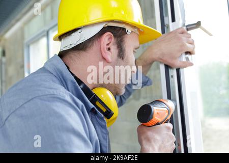 man drilling a hole in a window frame Stock Photo