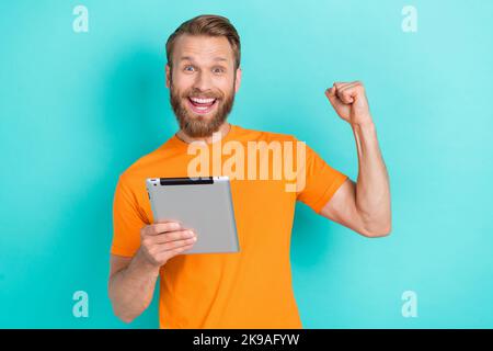 Photo of hooray beard guy hold tablet yell wear orange t-shirt isolated on teal color backgroiund Stock Photo
