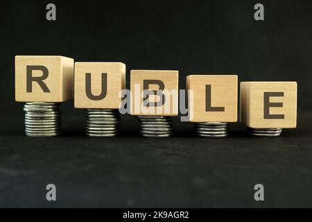 Russian ruble currency weakening, value depreciation and devaluation concept. Decreasing stack of coins on dark black background. Stock Photo