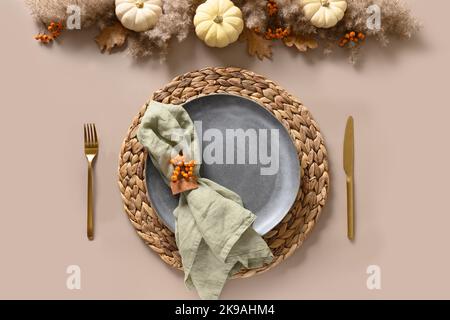 Thanksgiving day autumn table setting decoration in natural colors white pumpkins and orange berries on beige background. Top view. Copy space. Stock Photo
