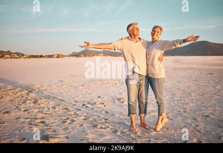 Love, beach and summer with a senior couple standing together on the sand on a sunny day. Travel, vacation and romance with a n elderly man and woman Stock Photo