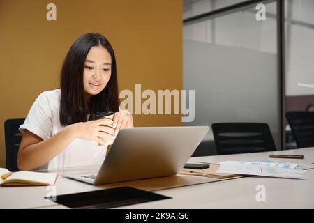 Elegant charming woman is working online on laptop in meeting room Stock Photo