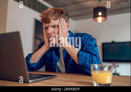 Ginger man reading something onlines and looking shocked Stock Photo