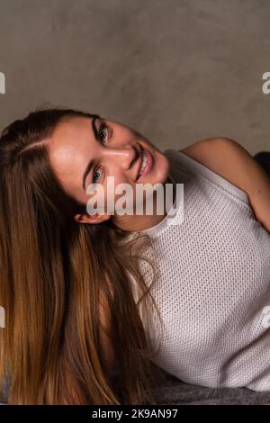 Smiling long haired woman in a white top looking into camera Stock Photo