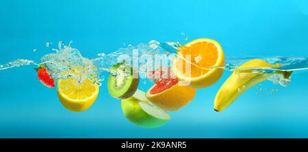 Fruits mix splashing into clear water on turquoise blue background Stock Photo