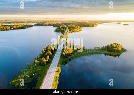 Road in the middle of lake landscape during a beautiful summery sunset in Northern Finland Stock Photo