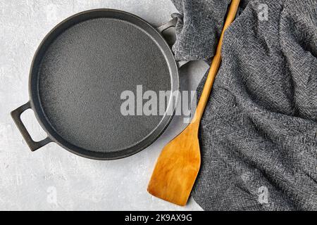Black cast iron empty frying pan, wooden spatula and gray kitche Stock Photo