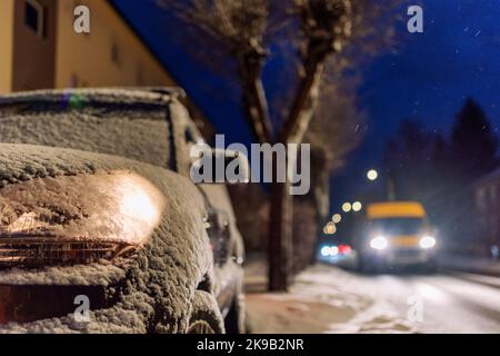 Parked car with light on covered by snow at night. Stock Photo