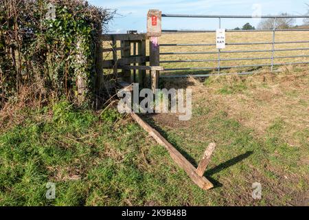 Directional arrow footpath sign mounted on a wooden post laying flat on its back on the grass pointing skyward Stock Photo