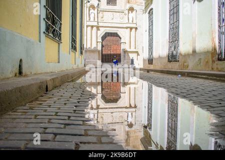 A colonial door and building reflect on water puddle in a cobblestone in Old Havana. Stock Photo