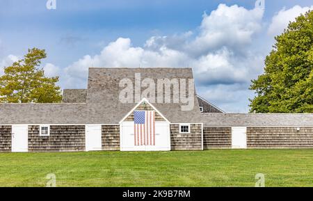 Old Wainscott barn with an American Flag hanging on the front Stock Photo