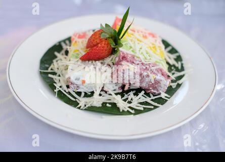 Rainbow Swirl Cake with strawberry fruit. Square rainbow cake on a plate Stock Photo
