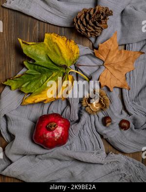 Autumn flat lay composed of pomegranate, chestnuts, pine cone and colorful dry leaves Stock Photo