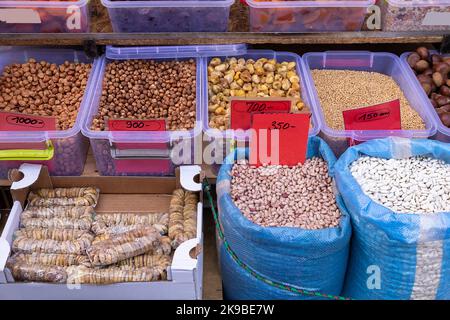 Kidney beans in sacks and wheat in plastic container with nuts piles sold on market Stock Photo