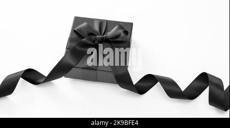 Black Friday Sale and Christmas presents concept. Gift box with black ribbon isolated against white background, Stock Photo