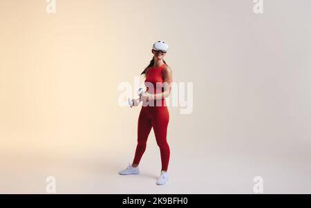 Female gamer enjoying an immersive virtual reality experience. Woman smiling cheerfully while exploring 3D technology. Happy young woman wearing a vir Stock Photo