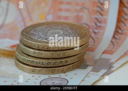 Bank of England, Sterling bank notes, with two pound coins showing inscription, 'Standing on the shoulders of giants'. Coins & note hard currency cash Stock Photo