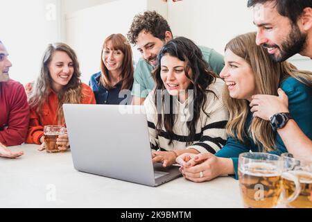 Group of young friends standing around a laptop computer watching social network content or studying together at home - people and technology lifestyl Stock Photo