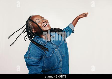 Cheerful woman smiling and whipping her dreadlocks while standing