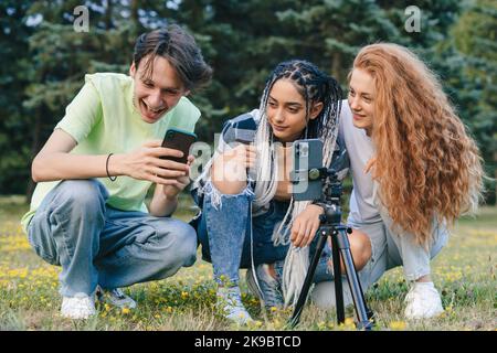 Generation Z friends standing in the park watching viral videos on the internet, laughing and enjoying their free time together. Modern content Stock Photo