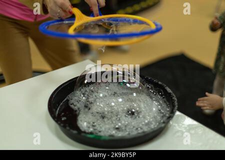 Bubbles. Soap solution for inflatable bubbles. Liquid for entertainment. Details of children's holiday. Liquid for inflating balls. Stock Photo