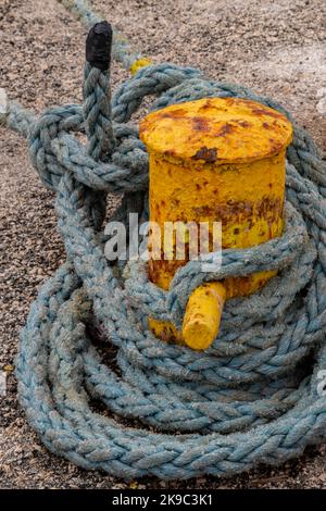 harbour mooring bollard on the dockside in a marina or port for tying up an berthing ovessels yachts and ships. Stock Photo