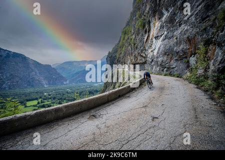 Male road cyclist descending the balcony road from Bourg d'Oisans to Villard Notre Dame, French Alps. Trying to beat the bad weather home. Stock Photo