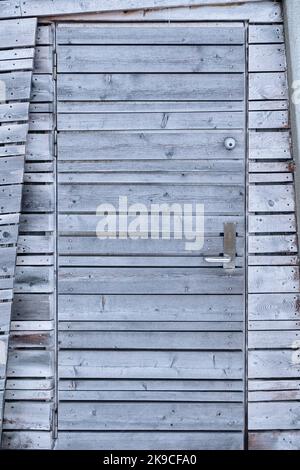 Weathered aged wooden grey door of the cottage in backcountry Stock Photo