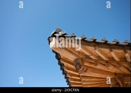 Traditional oriental wooden temple roof corner with black tile and blue sky Stock Photo