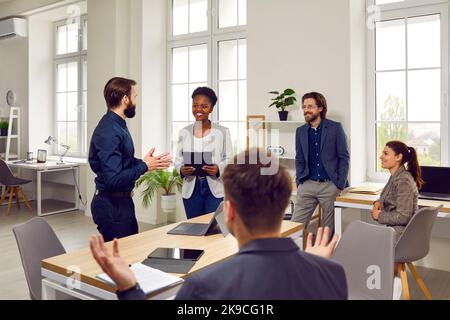 Smiling friendly coworkers having fun discussing work together at office meeting. Stock Photo