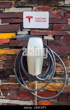 Alcantara, Spain - Oct 6th, 2022: Tesla Electric car charging station at rural enviroment. Natural rust slate wall. Alcantara Caceres, Spain. Stock Photo