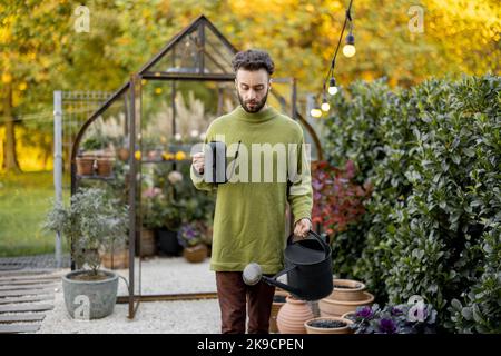 Stylish guy with watering can in garden Stock Photo