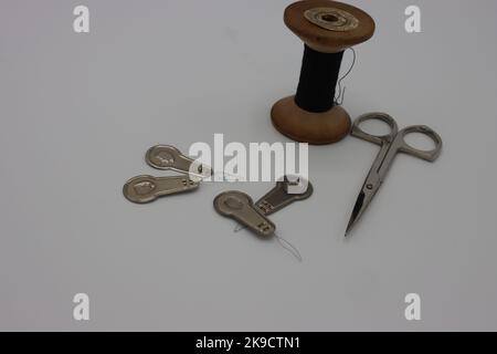 Sewing accessories on a white background. Needle threaders, thread and metal scissors Stock Photo