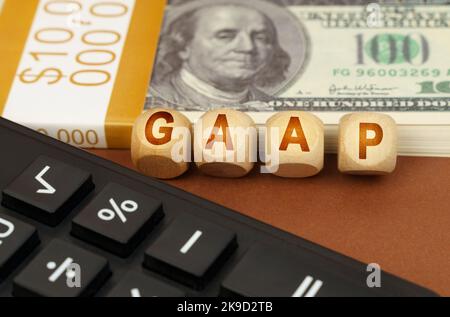 Business concept. On a brown surface are dollars, a calculator and wooden cubes with the inscription - GAAP Stock Photo