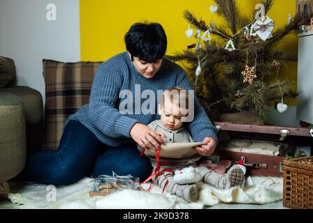 Premium Photo  Merry christmas and happy holidays! cheerful grandma and  her cute grand daughter girl exchanging gifts. granny and little child  having fun near tree indoors. loving family with presents in