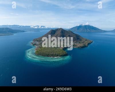 A fringing reef grows along the edge of a remote, volcanic island near Alor, Indonesia. This region is known for its high marine biodiversity. Stock Photo