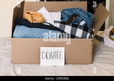 Cardboard box full of clothes to donate. Home cleaning, reuse, sustainable lifestyle Stock Photo