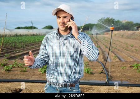 Portrait of farmer talking on phone on vegetable field Stock Photo