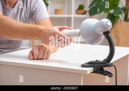 The man changes the lamp. Energy-saving lamp. Replacement of an energy-saving lamp. Stock Photo