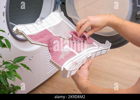 A housewife woman cleans the lint filter of the washing machine or tumble  dryer Stock Photo - Alamy